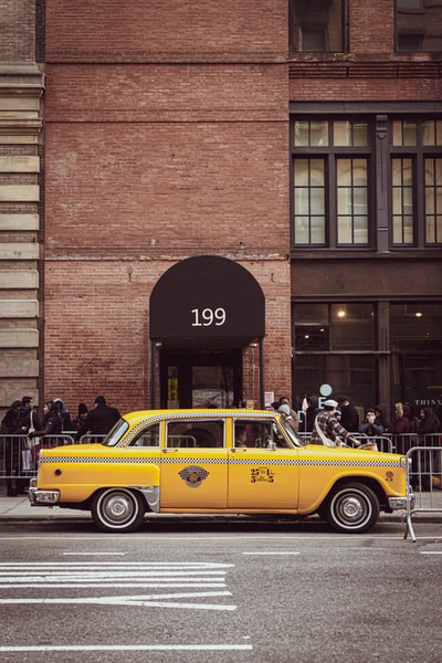 黄色出租车停在棕色砖房旁